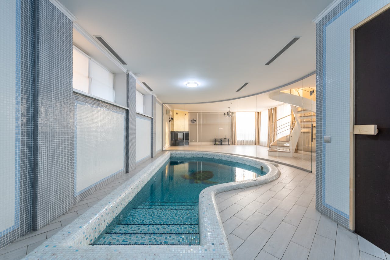 about-img Serene indoor pool area with modern design and spiral staircase.