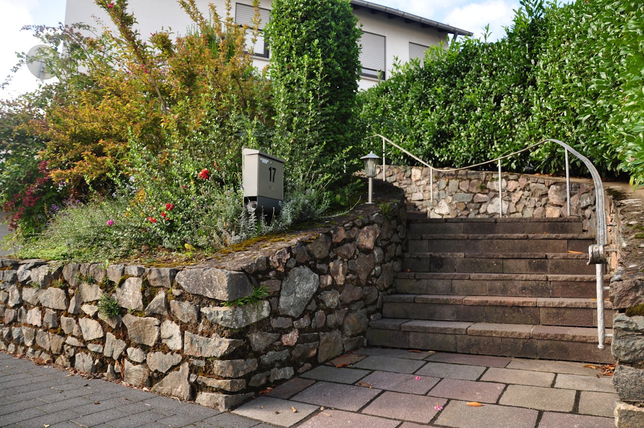 Beautiful stone staircase surrounded by colorful bushes and greenery in an outdoor garden setting.
